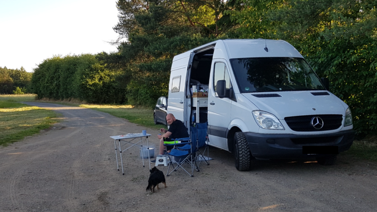 was ist vollzeit vanlife alex sitzt im stuhl vor dem diy sprinter auf einem parkplatz in deutschland